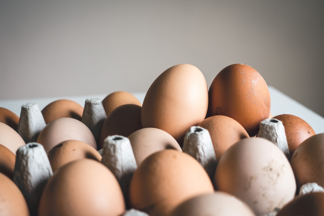 A close-up of a budget shopping list next to fresh eggs and spinach.