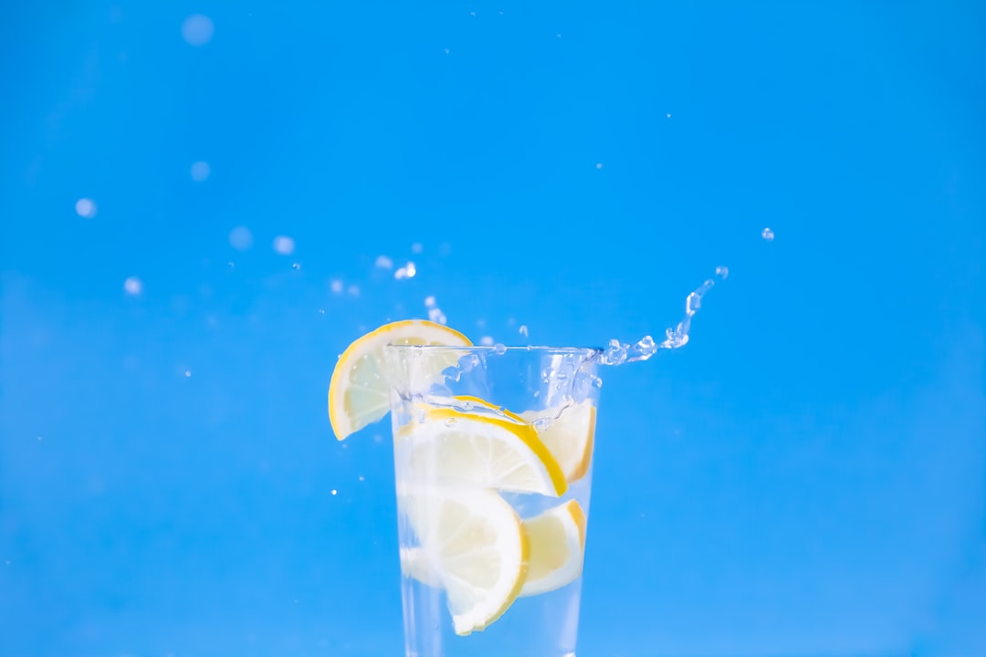 Intermittent Fasting Headaches: Why They Happen and When to Stop 1 A glass of water with a slice of lemon and a pinch of salt on a wooden table, representing hydration for fasting relief.