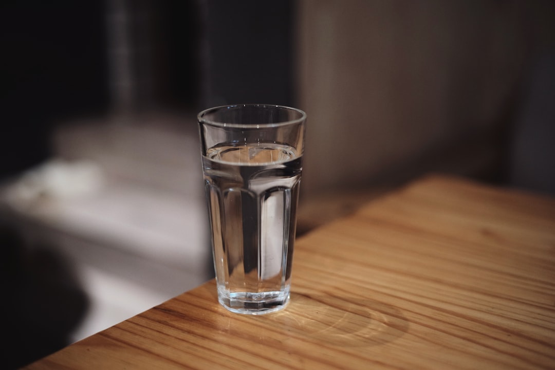 A glass of water with lemon slices on a clean wooden table, representing hydration during the first week of keto.