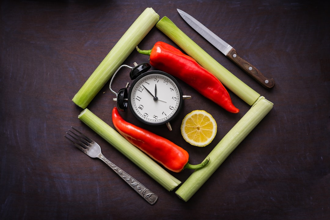An analog clock showing midnight next to a healthy meal prep container on a dark, professional desk.