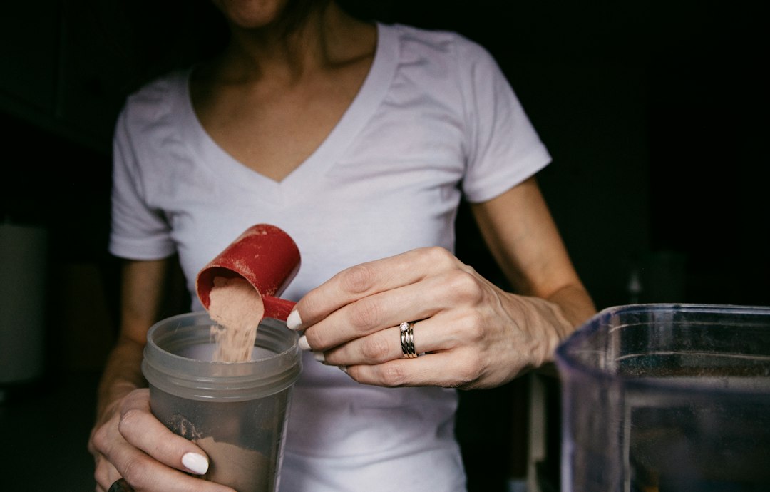 A clean setup of workout powder supplements on a kitchen counter next to a glass of water.