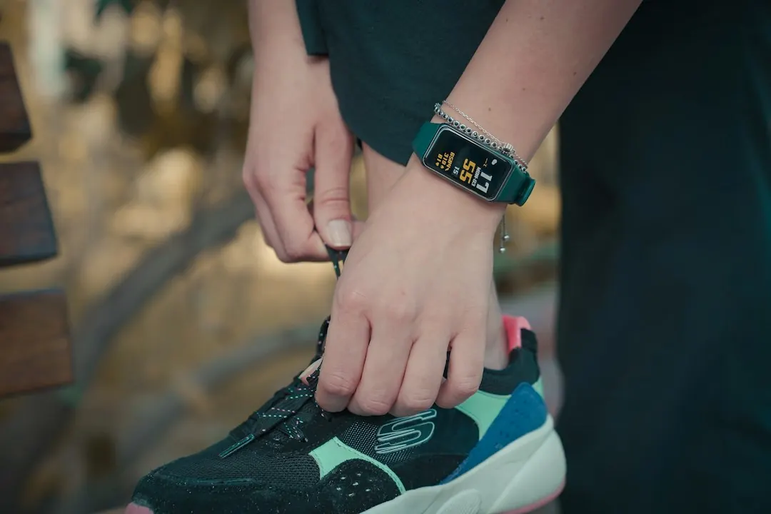 A person wearing a fitness tracker walking outdoor on a sunny path to increase daily NEAT step count.